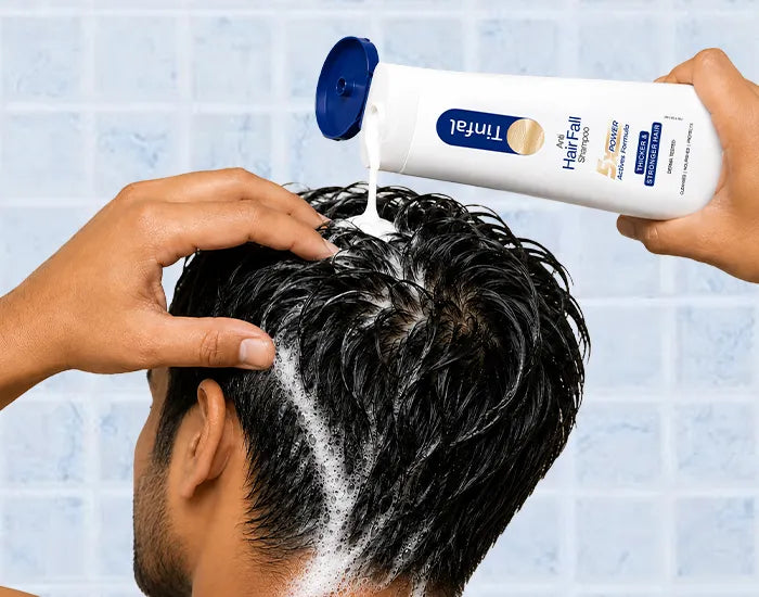 A person washing their hair with a white foam lather 