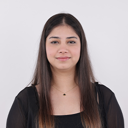 A woman with long dark brown hair wearing a black sheer top 