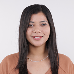 A smiling young woman with long dark hair, wearing a brown top 